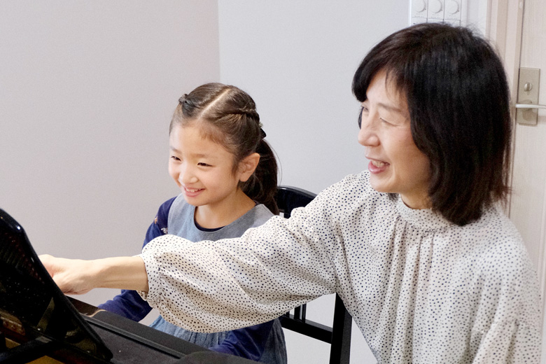 ピアノレッスンをする先生と笑顔の生徒さんの写真